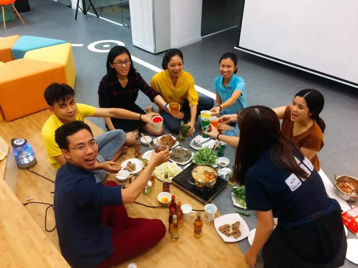 Colleagues sharing a hot pot meal on the floor of the office.