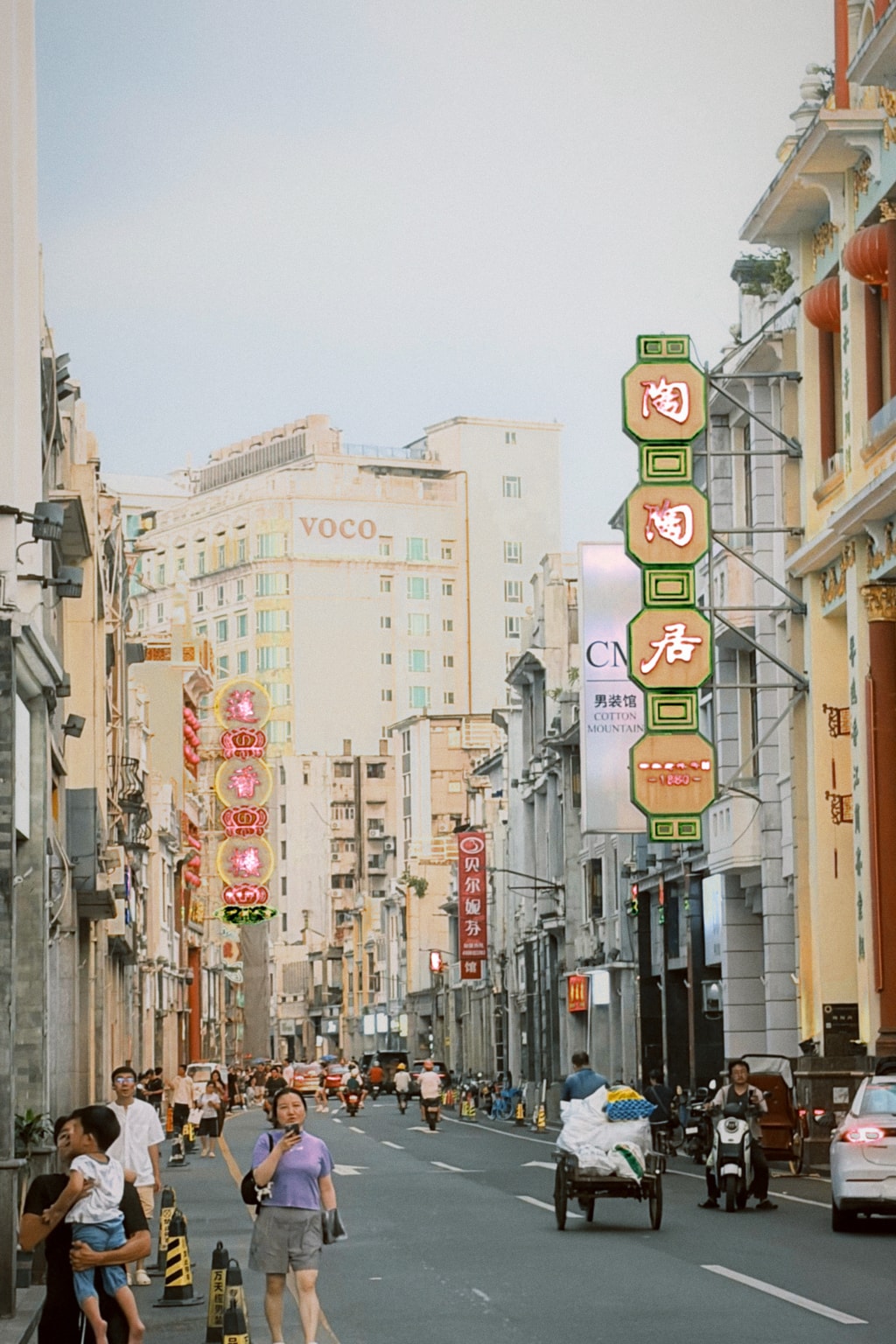 Old Guangzhou street at dusk with neon signs for Tao Tao Ju (est. 1880) and Lin Heung Lau teahouses, pedestrians and motorbikes below