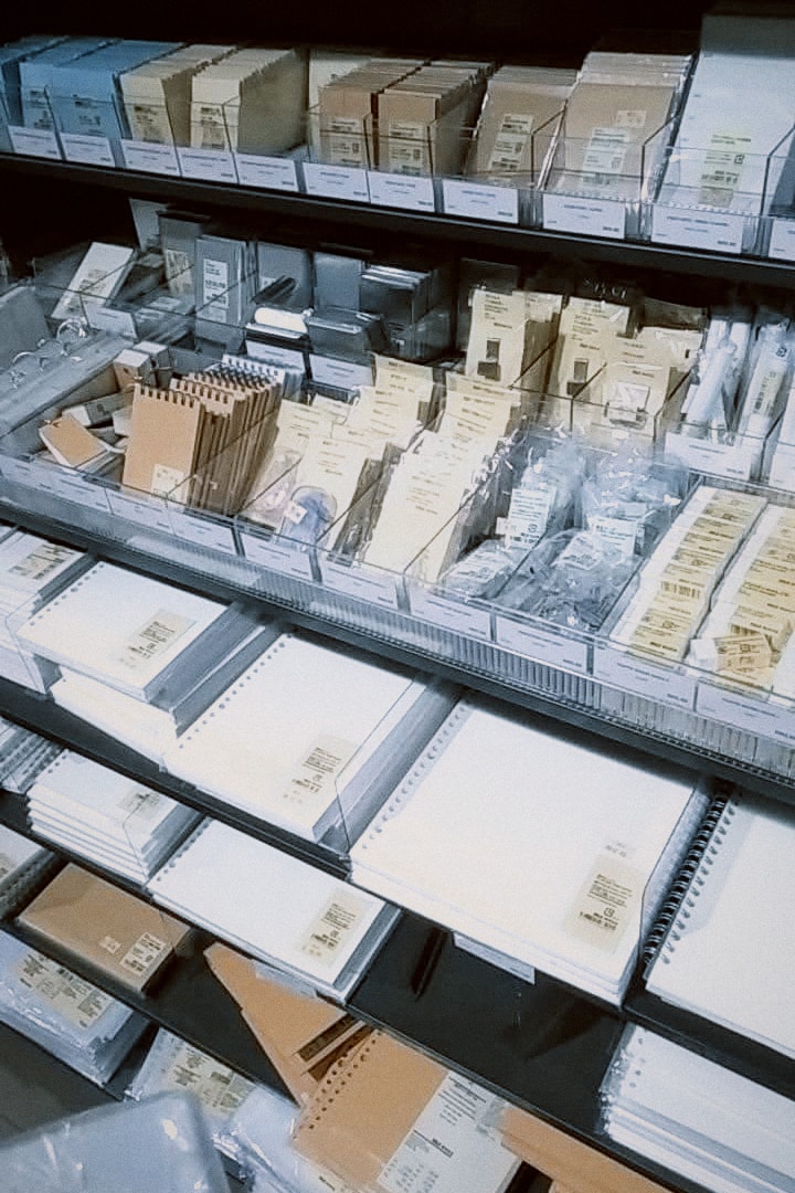 Shelves of stationery and small boxes in a Muji store.